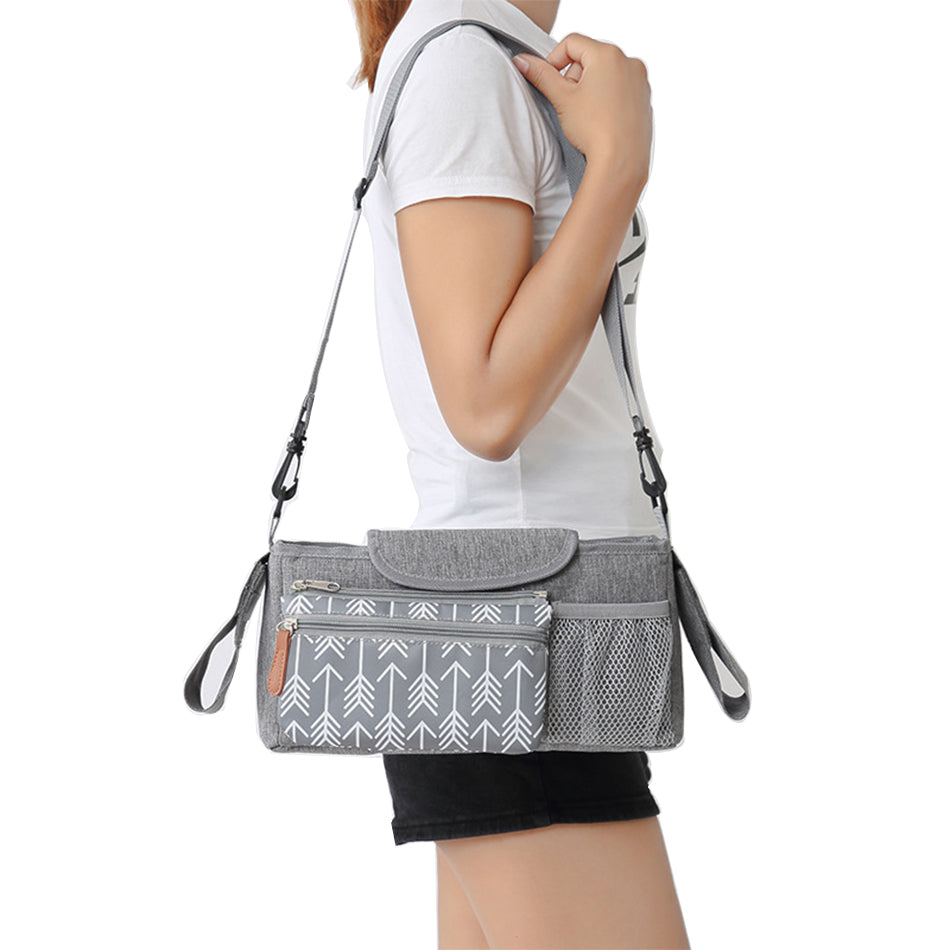 Person wearing a gray crossbody bag with arrow pattern on a white Baby Pram Caddy - Black Nursery Bagbackground