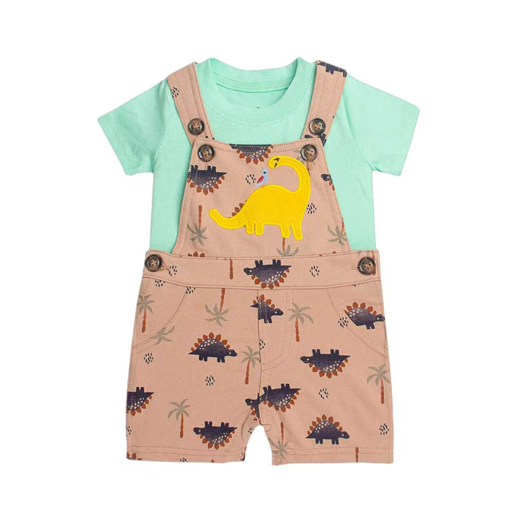 A baby boy's two-piece outfit featuring a mint green short-sleeve t-shirt layered under dusty pink dinosaur-printed overall shorts. The outfit includes a large yellow long-necked dinosaur graphic on the chest and brown button details on the bib.