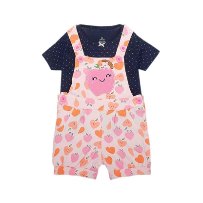 A baby girl's short-sleeve romper set featuring a pink peach print overalls vest layered over a navy blue short-sleeve top with white polka dots. The front of the overalls has a large pink peach applique with a smiling face and a small bunny detail.